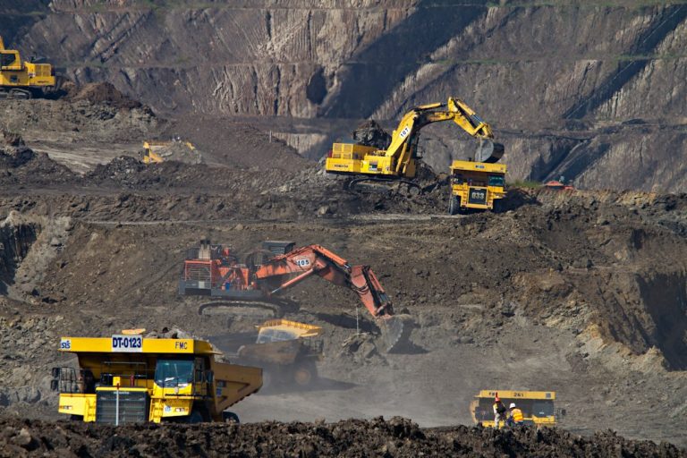 Excavators and haul trucks working at an open-pit coal mine in Indonesia; illustrative photograph.